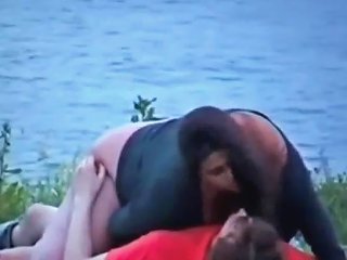 A Man Secretly Filming A Woman Of Larger Size Engaging In Sexual Activity With Her Partner Near A Body Of Water